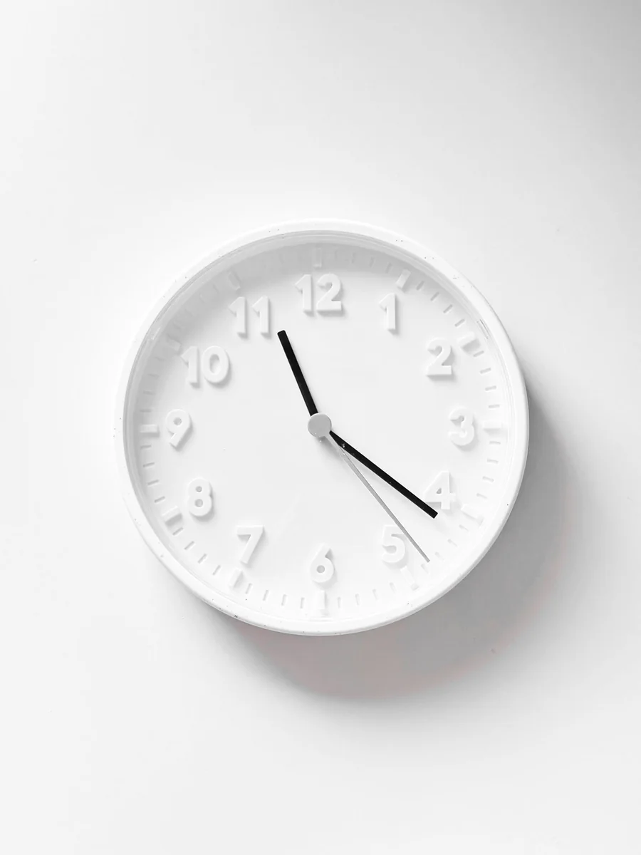 ساعة حائط دائرية باللون الأبيض الكامل مع أرقام بارزة وعقارب سوداء، تظهر بتصميم مينيمالي نظيف على خلفية بيضاء.